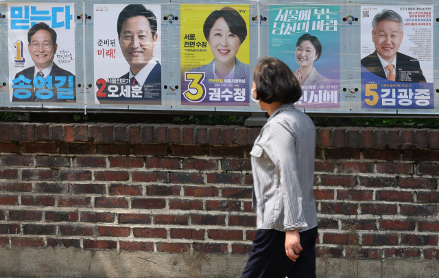 제8회 전국동시지방선거 공식 선거운동 첫날인 19일 오후 서울 종로구 예술가의 집 울타리에 부착된 후보들의 벽보 앞으로 시민이 지나가고 있다. 연합뉴스