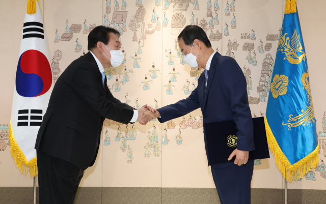 윤석열 대통령이 21일 서울 용산 대통령실 청사에서 한덕수 국무총리에게 임명장을 수여한 뒤 손을 잡고 있다. 연합뉴스