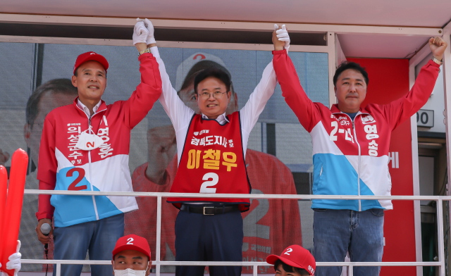 21일 경북 의성군 안계시장을 찾은 이철우(가운데) 6.1 지방선거 국민의힘 경북도지사 후보와 이영훈(왼쪽) 의성군수 후보, 변영송(오른쪽) 의성군의원 후보가 연단에서 손을 잡고 지지를 호소하고 있다.