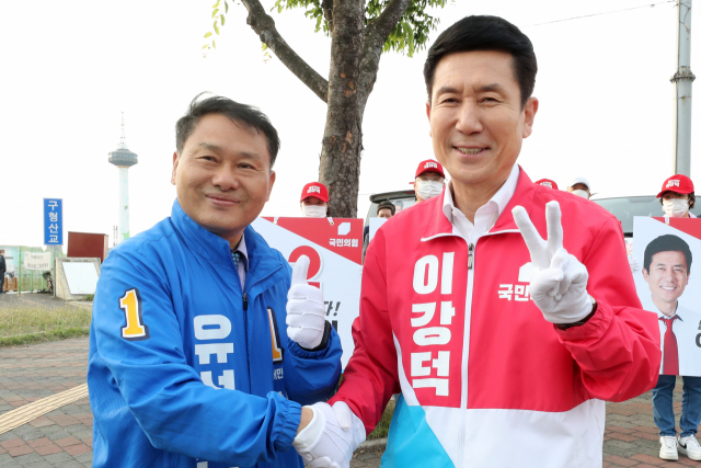 6·1 지방선거 공식 선거운동이 시작된 지난 19일 오전 경북 포항시 남구 해도동 형산교차로에서 포항시장 선거에 맞붙은 이강덕 국민의힘 후보(오른쪽)와 유성찬 더불어민주당 후보가 깨끗한 경쟁을 다짐하며 손을 잡고 있다. 연합뉴스
