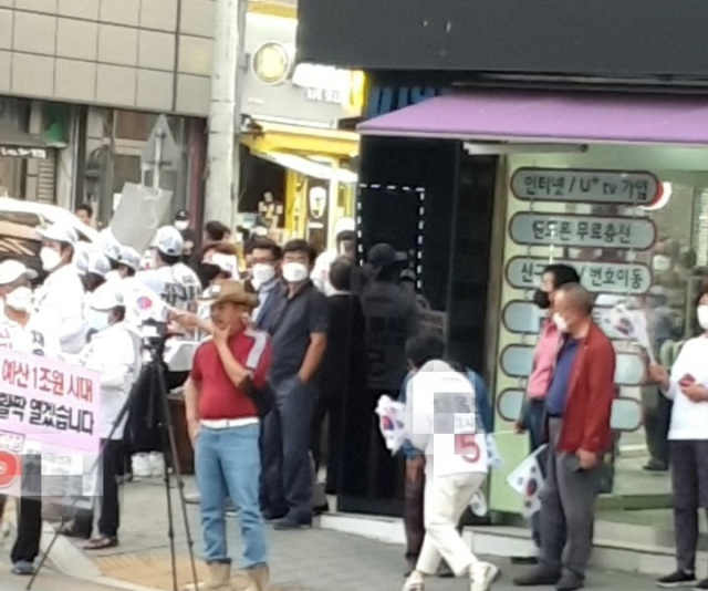 지난 23일 문경시장 선거에 출마한 A후보 유세 현장에서 한 운동원이 태극기를 청중들에게 나눠주고 있다. 독자 제공