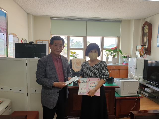 이수헌 매헌초등학교 후원회 명예회장이 24일 매원초등학교를 찾아 김선희 교장에게 문집 발간 후원금 100만원을 전달하고 있다. 이현주 기자