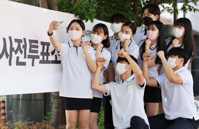 제8회 전국동시지방선거 사전투표 첫날인 27일 오후 경기도 수원시 장안구 연무동행정복지센터에 마련된 투표소에서 투표를 마친 삼일공업고등학교 3학년 학생들이 인증샷을 찍고 있다. 연합뉴스