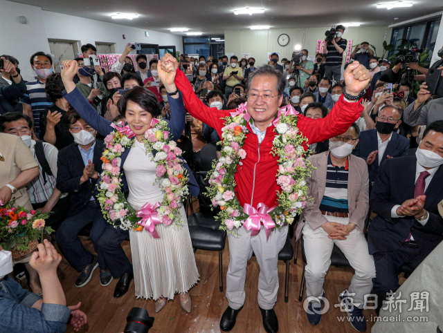 제8회 전국동시지방선거일인 1일 오후 국민의힘 홍준표 대구시장 후보가 대구 중구 삼덕동 마련된 선거사무소에서 당선이 확실시 되자 꽃다발을 목에 걸고 부인 이순삼 여사와 함께 기념 촬영을 하고 있다. 안성완 기자 asw0727@imaeil.com