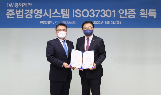 신영섭 JW중외제약 대표이사(오른쪽)가 지난 2일 서울 서초동 본사에서 이원기 한국컴플라이언스인증원장에게 ISO37301 인증서를 받은 뒤 기념촬영을 하고 있다. 사진=JW중외제약 제공