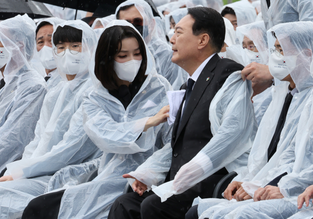 6일 오전 서울 동작구 국립서울현충원에서 열린 제67회 현충일 추념식에서 김건희 여사가 비에 젖은 윤석열 대통령의 옷을 닦아주고 있다. 연합뉴스