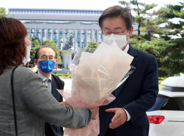 더불어민주당 이재명 의원이 7일 오전 국회 의원회관에 첫출근하며 지지자로부터 꽃다발을 받고 있다. 연합뉴스