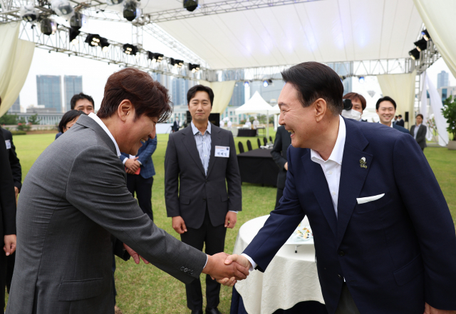 윤석열 대통령이 12일 오후 서울 용산 대통령실 청사 잔디마당에서 열린 영화관계자 초청 만찬에서 한국 배우 최초로 칸국제영화제에서 남우주연상을 수상한 배우 송강호와 인사하고 있다. 뒤에 서 있는 배우 박해일은 칸 영화제에 출품돼 박찬욱 감독에게 감독상을 안긴 