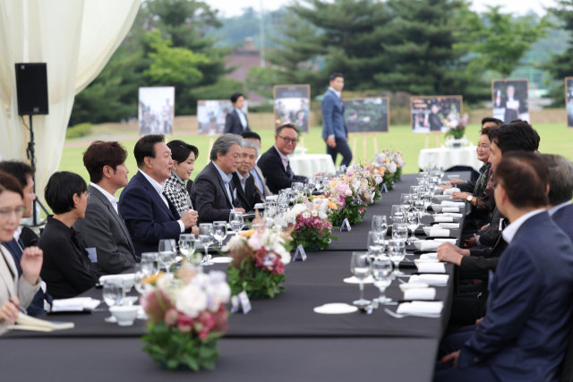 윤석열 대통령이 12일 오후 서울 용산 대통령실 청사 잔디마당에서 열린 영화관계자 초청 만찬에서 참석자들과 대화하고 있다. 이날 행사에는 한국 배우 최초로 칸국제영화제에서 남우주연상을 받은 배우 송강호와 감독상을 수상한 박찬욱 감독(영화 헤어질 결심)등이 참석했다. 연합뉴스