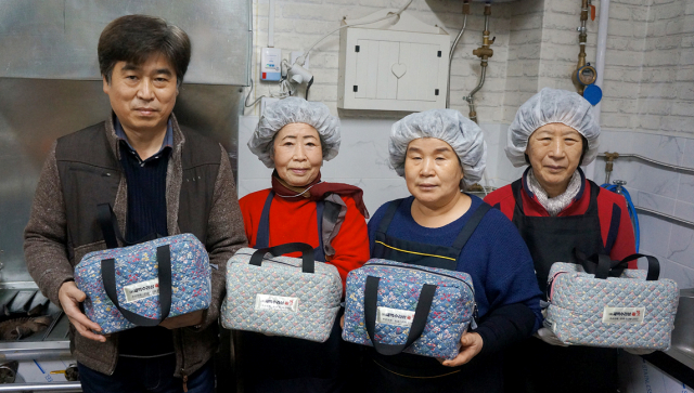 (주)새벽수라상 이남율 대표와 직원이 도시락을 들어보이고 있다