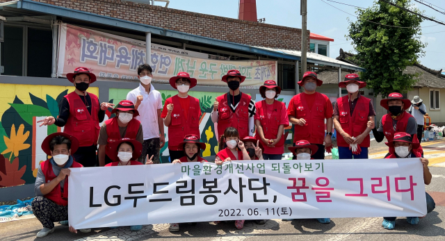 LG두드림봉사단 단원들과 구미 고아읍 괴평2리 주민들이 벽화 리모델링 봉사활동을 하며 기념촬영하고 있다. LG경북협의회 제공