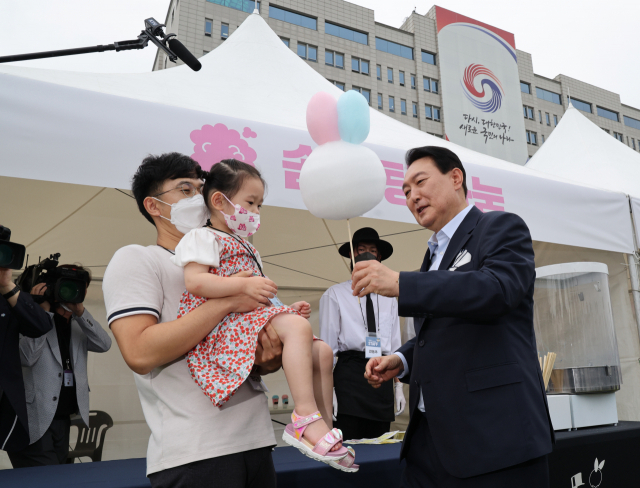 윤석열 대통령이 19일 오후 용산 대통령실 청사 앞 잔디광장에서 열린 대통령실 이전 기념 주민 초대 행사에서 한 어린이게 솜사탕을 건네주고 있다. 연합뉴스