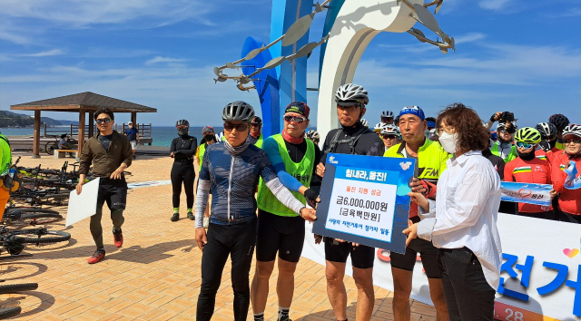 울진 산불극복위한 사랑의 자전거 라이딩 대원들이 울진 망양대게공원에서 산불극복 성금을 전달하고 있다.