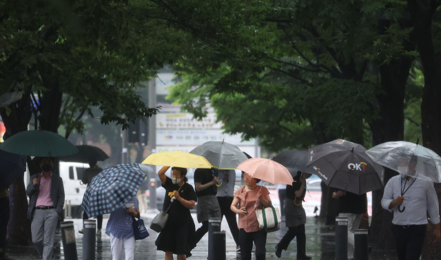 서울·인천·경기 지역에 호우주의보가 내려진 23일 오후 서울 여의도에서 시민들이 우산을 쓴 채 걸어가고 있다. 연합뉴스
