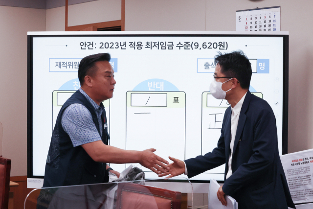 30일 오전 세종시 정부세종청사 최저임금위원회 회의실에서 열린 제8차 전원회의에서 내년도 최저임금을 9천620원으로 의결한 뒤 근로자 위원인 이동호 한국노총 사무총장(왼쪽)과 박준식 위원장이 악수를 하고 있다. 연합뉴스