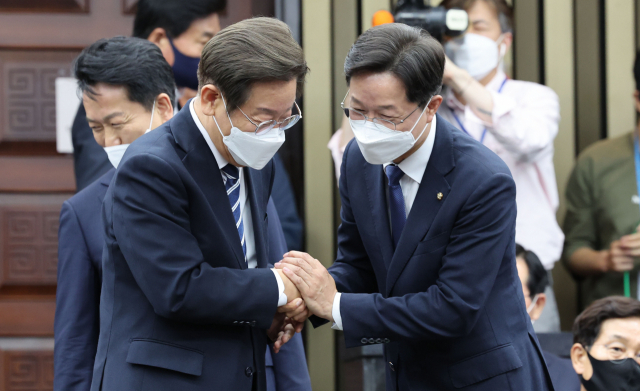더불어민주당 이재명 의원과 당대표 출마를 선언한 강병원 의원이 30일 오후 서울 여의도 국회에서 열린 의원총회에 참석하며 악수하고 있다. 연합뉴스