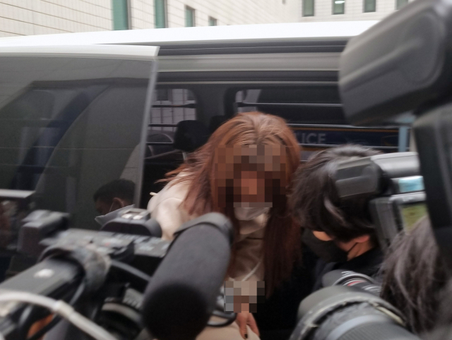 9호선 휴대전화 폭행 사건으로 구속된 20대 여성이 지난 3월 30일 오전 서울 강서경찰서 호송차에서 내리고 있다. 이 여성은 지난 16일 지하철 9호선 전동차 안에서 휴대전화로 60대 남성의 머리를 여러 번 내려친 혐의를 받고 있다. 연합뉴스
