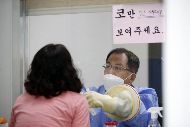 12일 오후 광주 북구 상시선별진료소에서 보건소 의료진이 검사 대상자들의 검체를 채취하고 있다. 연합뉴스