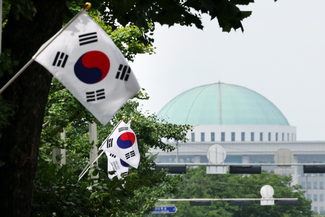 제74주년 제헌절인 17일 서울 영등포구 여의도동 거리에 게양된 태극기 뒤로 국회의사당이 보인다. 연합뉴스