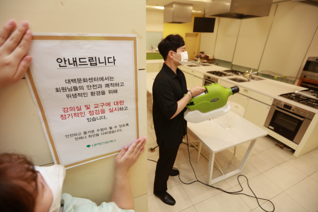 코로나19가 재확산 조짐을 보이는 가운데 19일 대구 중구 대구백화점 프라자점 문화센터에서 관계자들이 방역작업을 하며 방역 안내문을 붙이고 있다. 연합뉴스