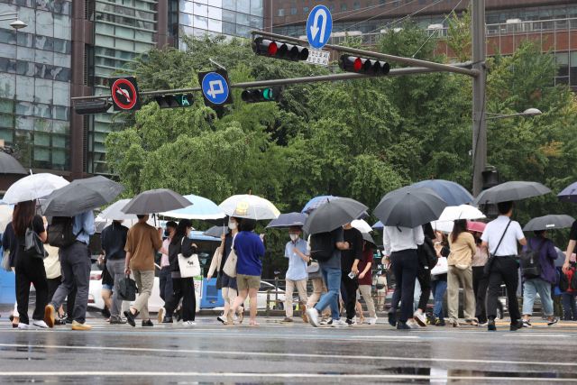 전국 곳곳 비 소식이 예보된 21일 오전 서울 종로구 광화문네거리에서 시민들이 우산을 쓴 채 이동하고 있다. 연합뉴스