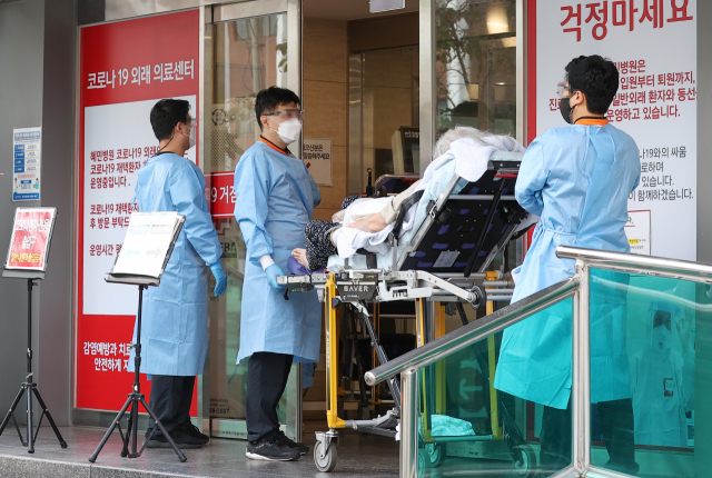 코로나19 위중증 환자 수가 54일만의 최다치(168명)를 기록한 26일 오후 서울 광진구 혜민병원에서 구급대원들이 코로나19 환자를 옮기고 있다. 연합뉴스