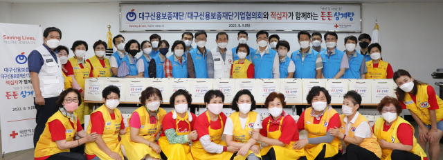 대구신용보증재단,대구신용보증재단기업협의회와 적십자사가 함께하는 든든삼계탕 나눔활동에 함께한 대구신용보증재단 임직원과 적십자 임직원 및 봉사원이 기념촬영을 하고 있다