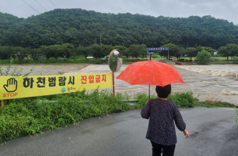 중부지역에 많은 비가 이어지는 9일 강원 원주시 호저면 산현리 칠봉체육공원으로 가는 외길이 하천 범람으로 막혀 일대 10여 가구가 고립되자 인근 주민이 이를 걱정하며 바라보고 있다. 연합뉴스