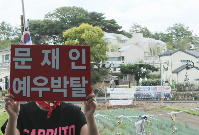 문재인 전 대통령에 반대하는 단체 회원들이 17일 낮 문재인 전 대통령 사저가 있는 경남 양산시 하북면 지산리 평산마을에 모여 문 전 대통령 수사, 전직 대통령 예우박탈 등을 주장하는 집회를 하고 있다. 한 반대단체 회원이 사저 앞에서 전직 대통령 예우를 박탈하라는 피켓을 들고 시위를 하고 있다. 연합뉴스