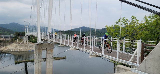경북도 명품 자전거길 탐사팀원들이 부항댐 출렁다리를 건너고 있다.