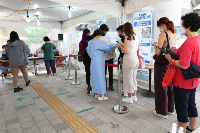 26일 오전 서울 마포구보건소에 마련된 선별진료소에서 시민과 외국인들이 검사를 받기 위해 문진표를 작성하고 있다. 연합뉴스