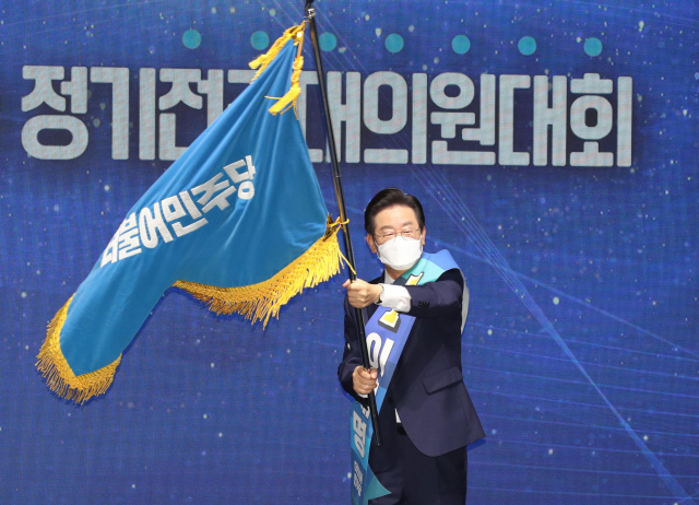 더불어민주당 이재명 신임 당 대표가 28일 서울 송파구 올림픽 체조경기장에서 열린 제5차 정기전국대의원대회에서 당 대표로 선출된 뒤 당기를 흔들고 있다. 연합뉴스