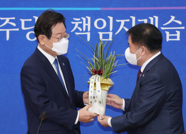 더불어민주당 이재명 신임 당대표가 30일 오전 서울 여의도 국회 대표실을 방문한 이진복 대통령실 정무수석으로부터 축하난을 받고 있다. 연합뉴스