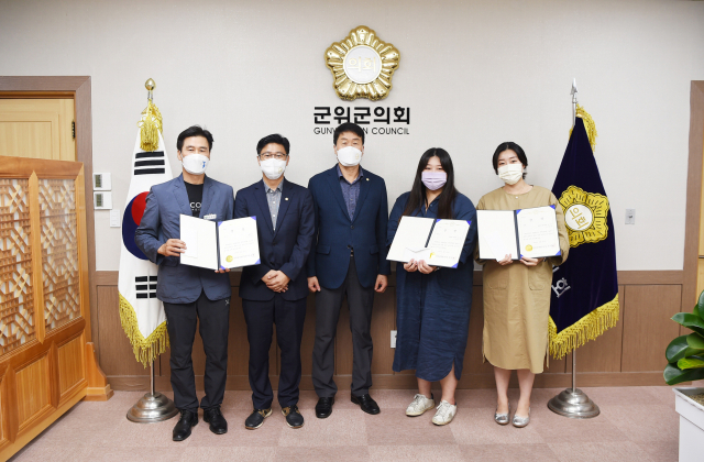 박수현(가운데) 경북 군위군의회 의장이 공모에 채택된 슬로건에 대해 시상하고, 우수 제안자들과 기념 사진을 촬영하고 있다. 군위군의회 제공
