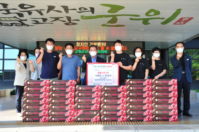 국립원예특작과학원 사과연구소가 군위군에 사과를 기탁하고 기념 사진을 촬영하고 있다. 군위군 제공