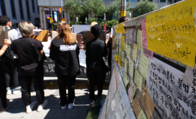 19일 서울 중구 신당역 10번 출구 앞에서 열린 스토킹 범죄 피해에 대한 대응책 촉구 기자회견하는 참가자들 뒤로 시민들의 추모 메시지가 붙어 있다. 연합뉴스