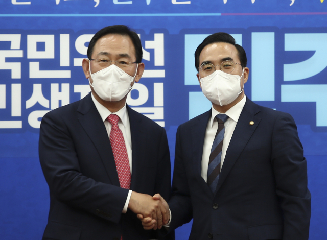 더불어민주당 박홍근 원내대표(오른쪽)가 21일 국회 본청 원내대표실을 예방한 국민의힘 주호영 원내대표와 악수하고 있다. 연합뉴스