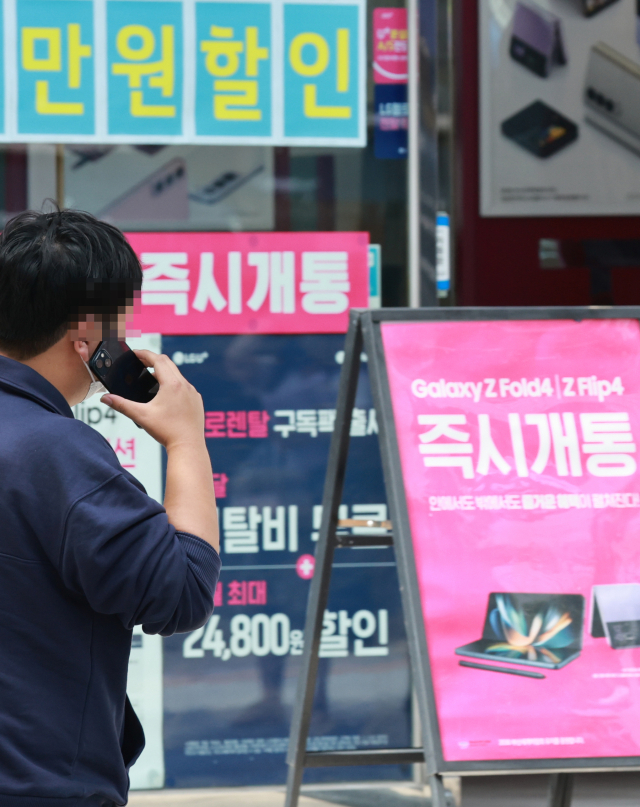 20일 서울 서대문구 대학가에서 한 학생이 통화를 하며 휴대전화 대리점 앞을 지나고 있다. 연합뉴스