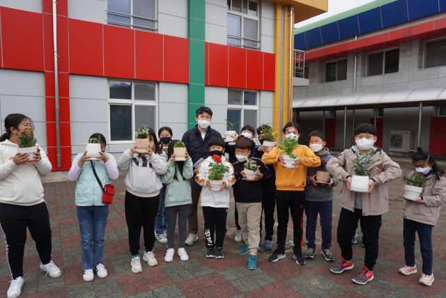 포항 기계초등학교 학생들이 교정에서 화분에 심은 꽃을 들고 환하게 웃고 있다. 기계초 제공.