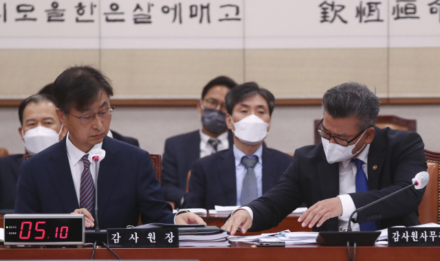 최재해 감사원장과 유병호 감사원 사무총장이 11일 국회에서 열린 법사위의 감사원 국정감사에서 답변 내용을 주고 받고 있다. 연합뉴스