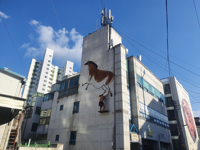 대구 달서구 진천동에 조성된 선사시대로 테마거리. 건물 벽면에 구석기 시대 벽화와 원시인 조형물이 설치돼 있다. 배주현 기자