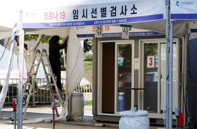 13일 오전 인천시청 앞 광장에 설치된 신종 코로나바이러스 감염증(코로나19) 임시 선별검사소에서 시설업체 관계자가 철거 작업을 하고 있다. 연합뉴스