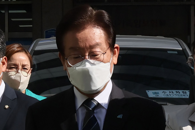 더불어민주당 이재명 대표가 민주연구원에 대한 검찰 압수 수색이 진행 중인 24일 오전 서울 여의도 더불어민주당 중앙당사 앞에서 입장을 밝히기 위해 취재진에게 다가서며 검찰 수사차량 앞을 지나고 있다. 연합뉴스