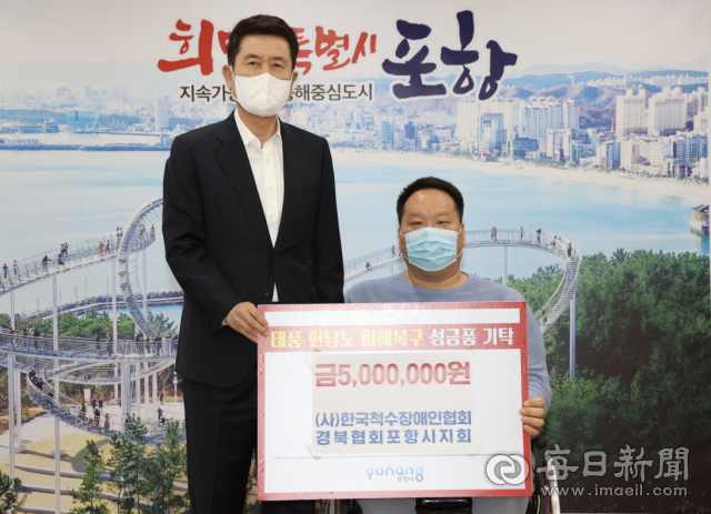 공지웅 (사)한국척수장애인협회 경북협회 포항시지회장(오른쪽)이 이강덕 포항시장에게 태풍 피해 이재민들을 위한 성품을 전달하고 있다. 포항시 제공