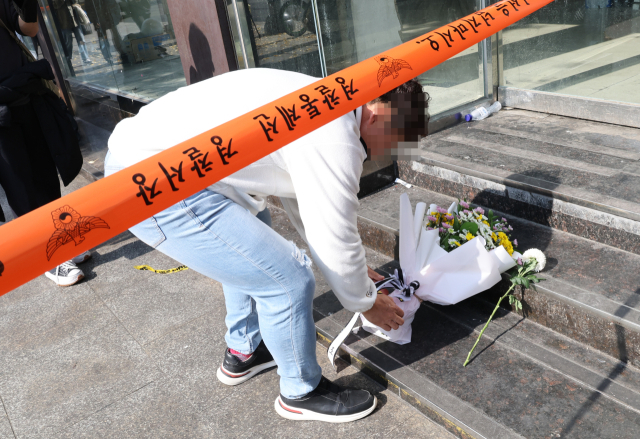 30일 한 시민이 이태원 압사 사고 현장에 추모꽃을 놓고 있다. 연합뉴스