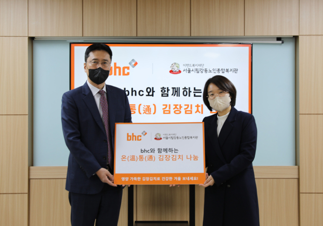 bhc그룹 허명수 전무(좌측)가 김장김치를 전달한 후 서울시립 강동노인종합복지관 이경화 부장(우측)과 함께 기념촬영을 하고 있다.