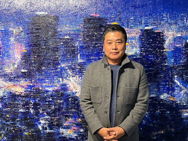 김성호 작가가 자신의 그림 앞에서 포즈를 취하고 있다. 이연정 기자