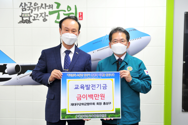 홍성구(왼쪽) 재대구 군위군향우회장이 김진열 군위군교육발전위원회 이사장에게 교육발전기금을 기탁하고 기념 사진을 촬영하고 있다. 군위군 제공