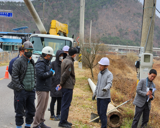 수자원공사가 문화재청의 원상복구 명령에 따라 전봇대를 뽑아낸 자리에 문화재조사위원이 땅 속에 문화층이 존재하는 것을 군위군 관계자에게 설명하고 있다. 이희대 기자