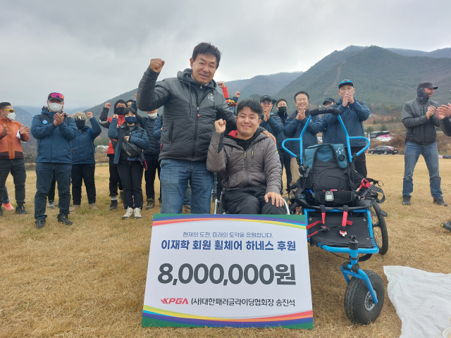 지난 13일 문경활공장에서 송진석(왼쪽) 대한패러글라이딩협회 회장이 이재학씨에게 휠체어 하네스를 기증한 뒤 함께 파이팅을 외치고 있다. 대한패러글라이딩협회 제공